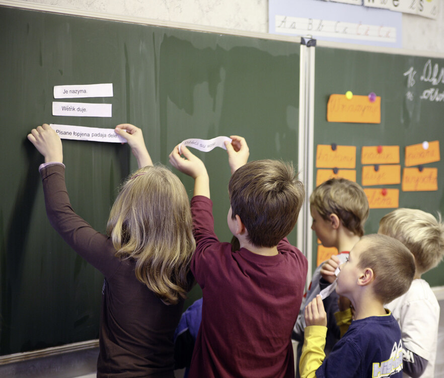 Kinder heften sorbisch beschriftete Zettel an eine Tafel.